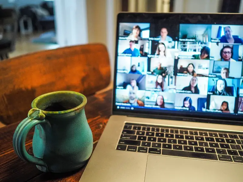 Mug next to an open laptop showing online call with multiple people