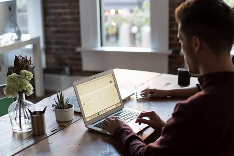 A man wearing brown long sleeves working in front of laptop