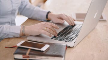 woman working on laptop computer next to notebook and smartphone