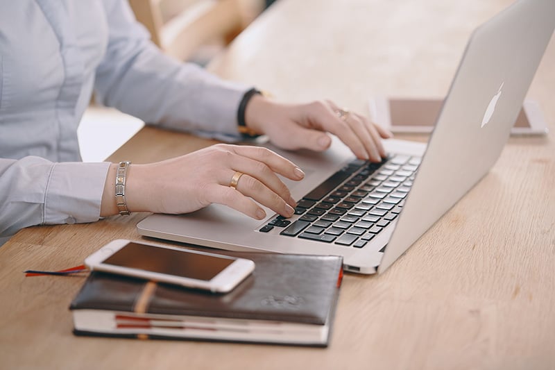 woman working on laptop computer next to notebook and smartphone