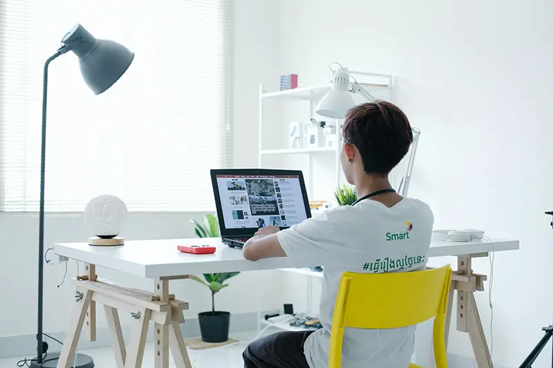 A young person sitting in front of laptop on white table