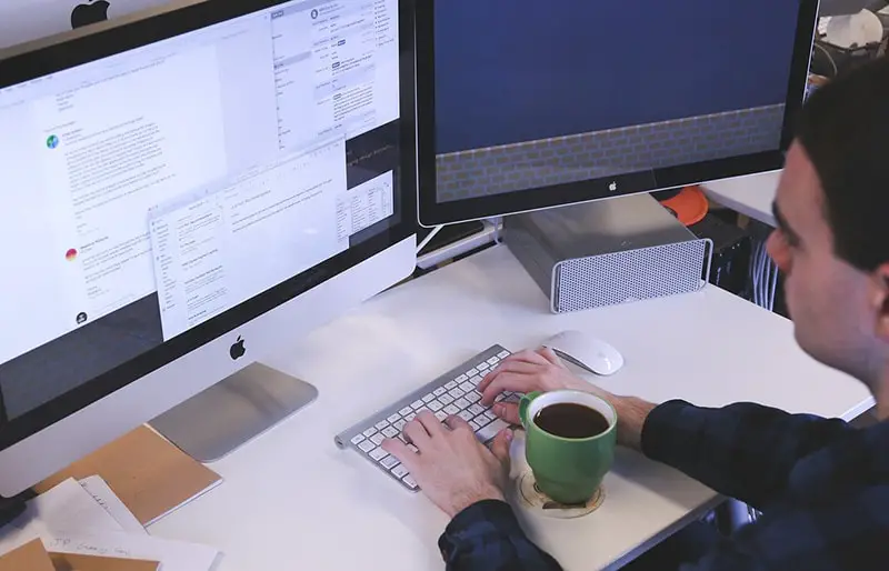 person typing on computer keyboard at desk in office