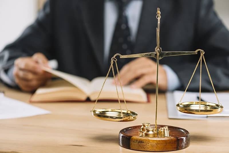 Lawyer reading a book at a desk - scales of justice on table