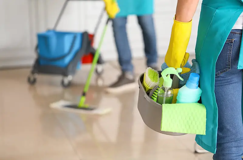Female janitor with cleaning supplies in office workplace