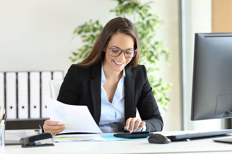 Businesswoman wearing suit working using a calculator in a desk at office