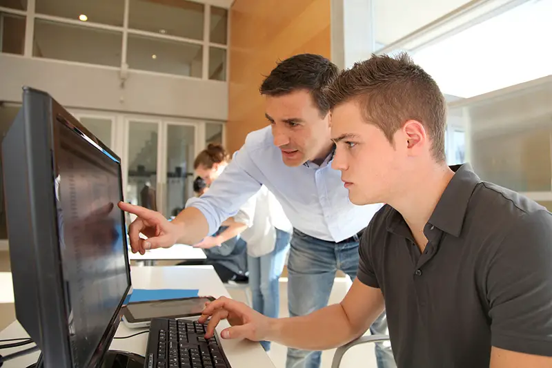 amn give training to an intern in front of computer