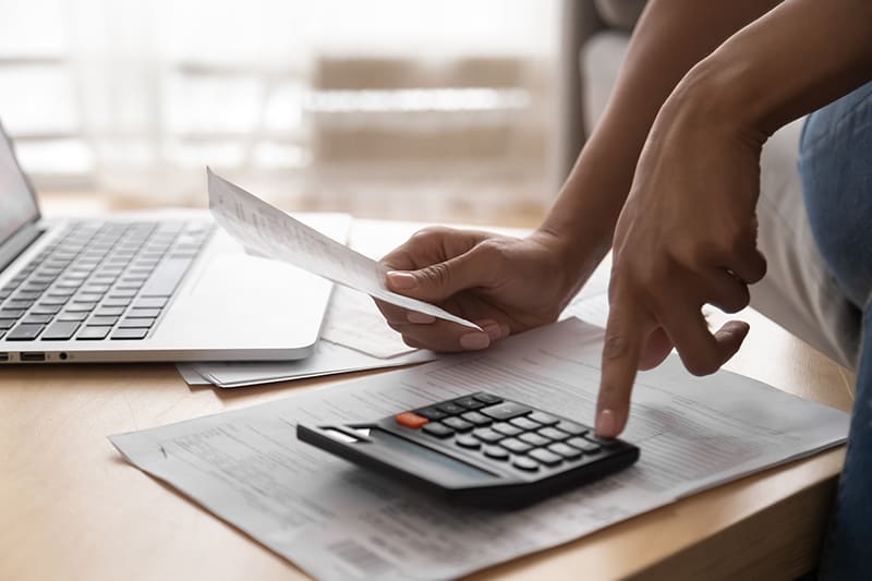 person holding a receipt and using calculator to calculate expenses