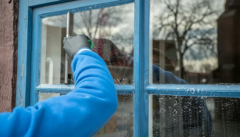 Person wearing gloves cleaning the window