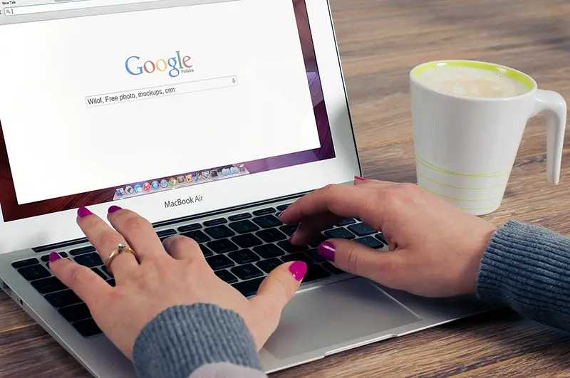 Woman wearing purple nail polish working on her MAcBoor Air laptop