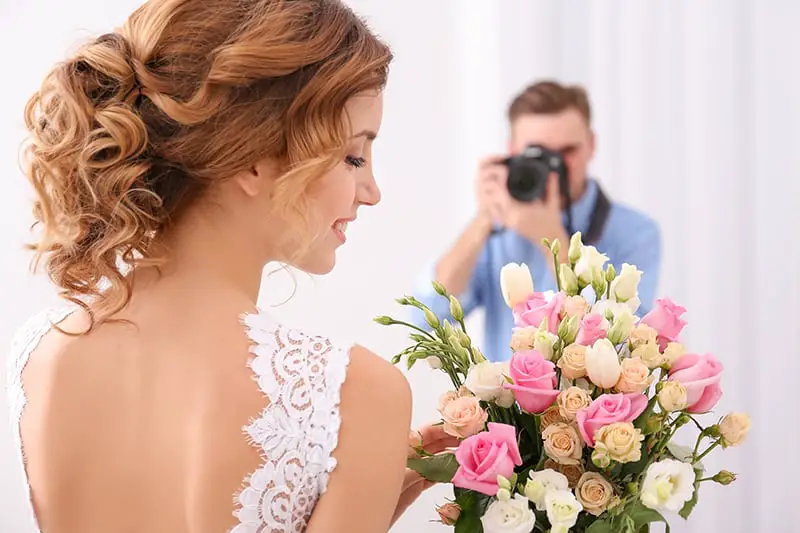 Wedding photographer taking photo of beautiful bride in studio