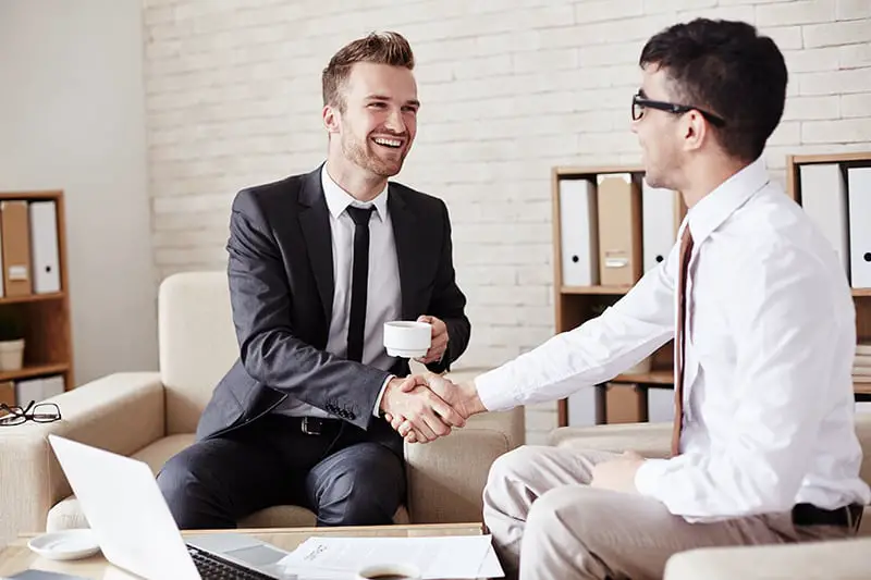 Business partners in formalwear greeting one another in office