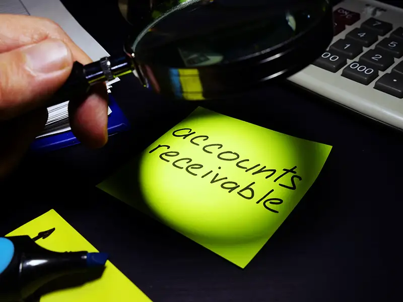 Account receivable text on green paper and a magnifying glass