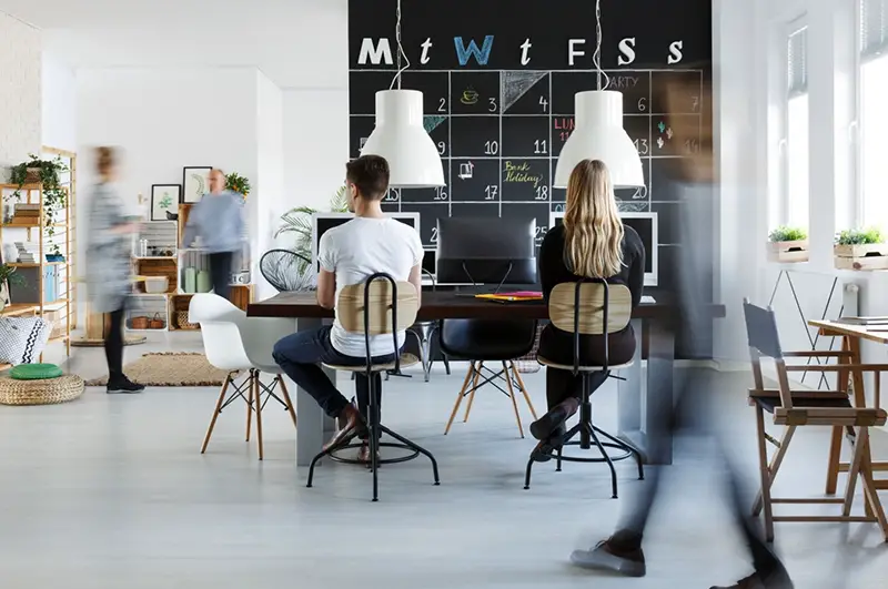 A woman and a man sitting in front of laptop