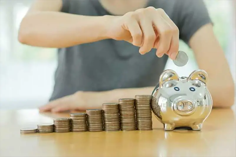 person putting coin into piggy bank