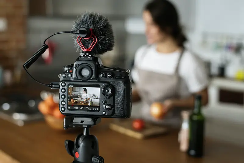 Female vlogger recording cooking related broadcast at home for video marketing