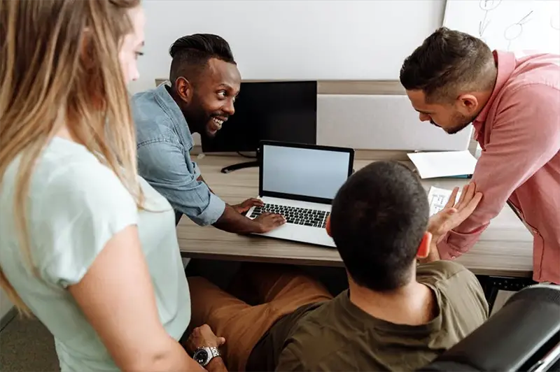 group of people having a discussion at work next ro desk with computer on it