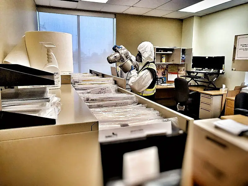 Person cleaning and disinfecting office