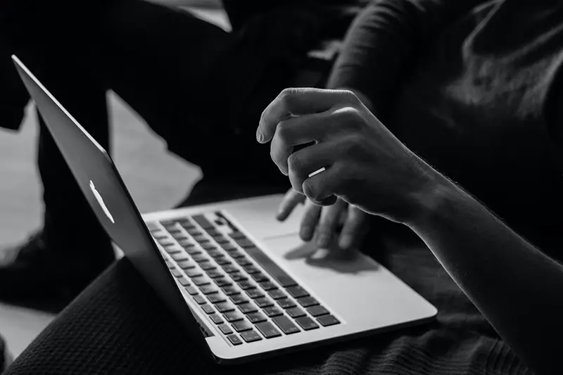 Grayscale photo of person using MacBook