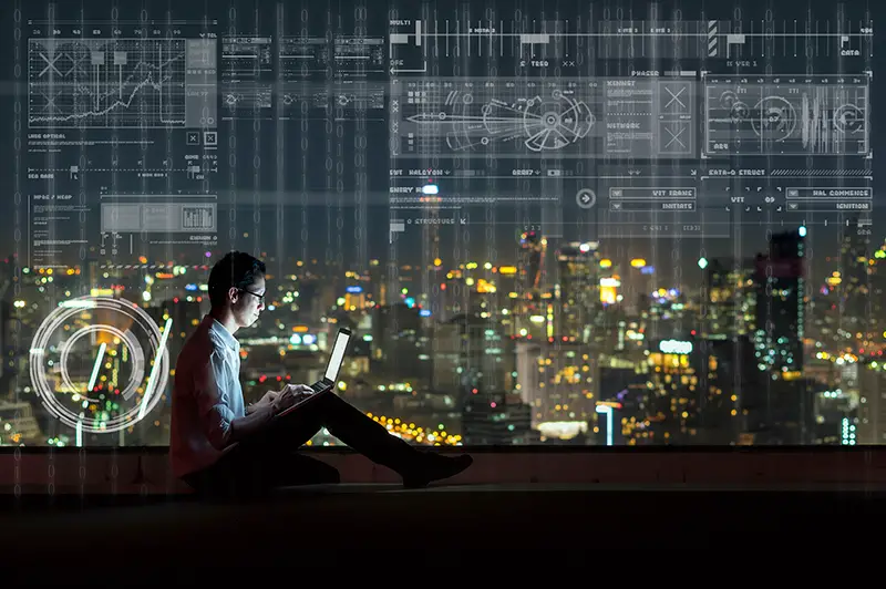 Asian businessman sitting and using the laptop showing digital virtual screen over the cityscape background at night time, Business technology and innovation concept