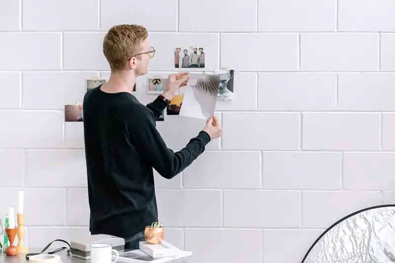 A young man attaching images on the white wall