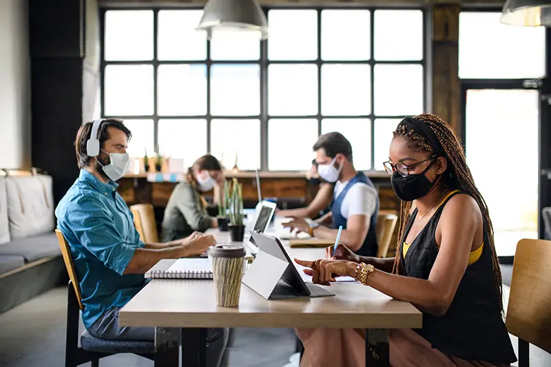 Business people with face masks indoors in office, back to work after coronavirus lockdown.