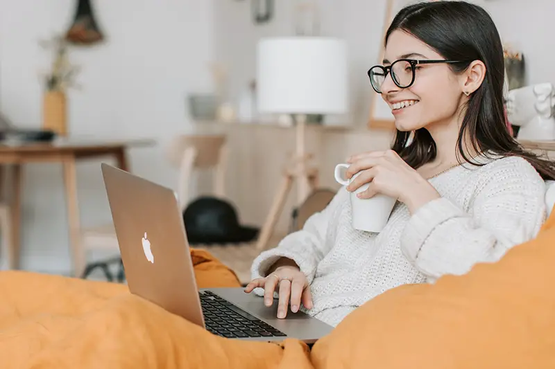 Woman having coffee while using laptop