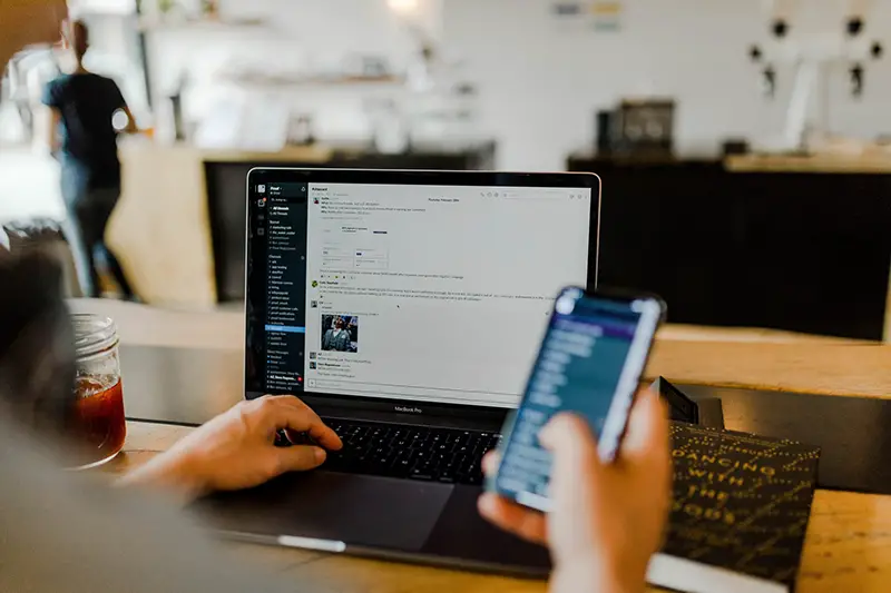 person using app on phone and laptop