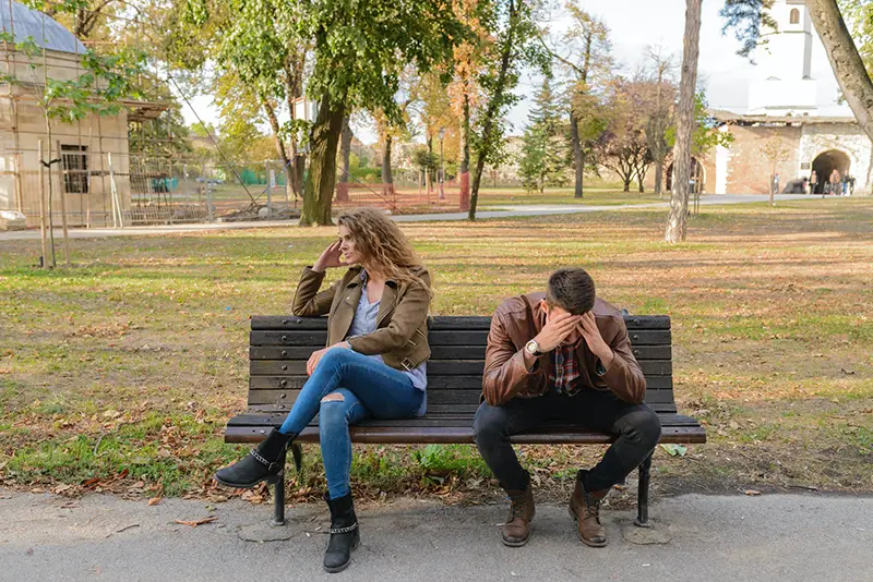 Unhappy young couple sitting on the bench