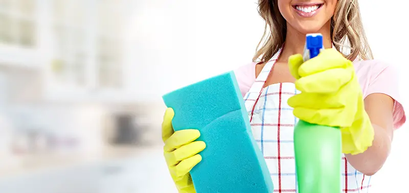 Happy woman holding cleaning materials.