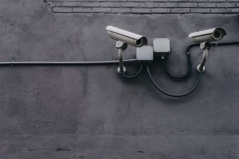 two grey securoty cameras mounted to a wall