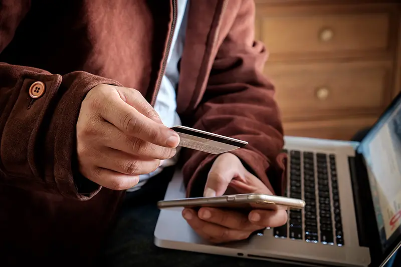 Man's hands holding a credit card and using smart phone for online shopping