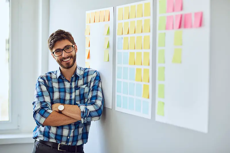 Start-up businessman leaning against wall with sticky notes
