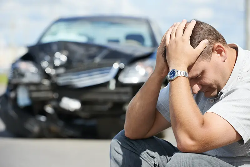 Stressed man sitting near the car accident area