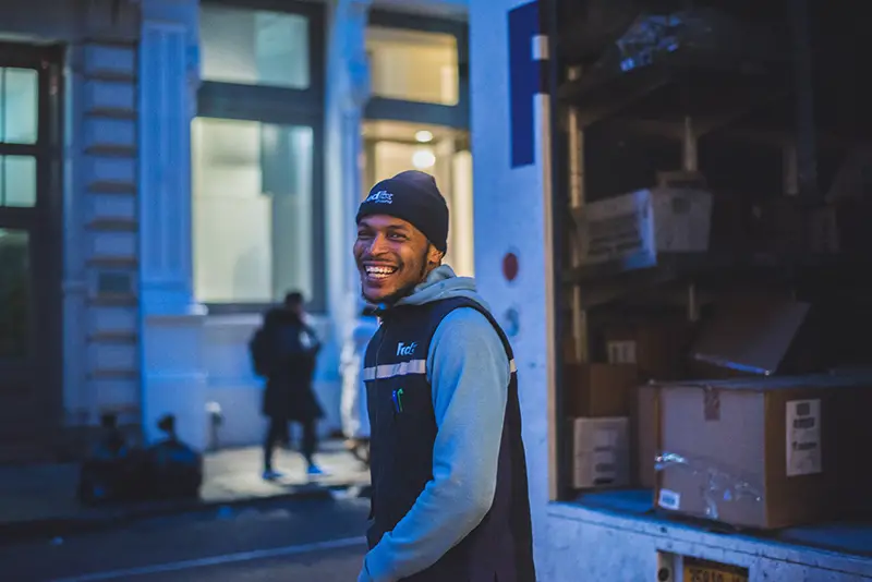 smiling man – courier next to delivery van full of parcels