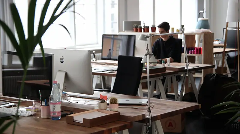 Adult male working on a computer sat at a desk in contemporary office