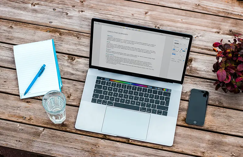 Silver macbook and smartphone on the top of wooden table