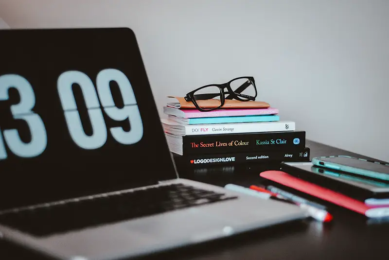 open silver MacBook pro next to a stack of books