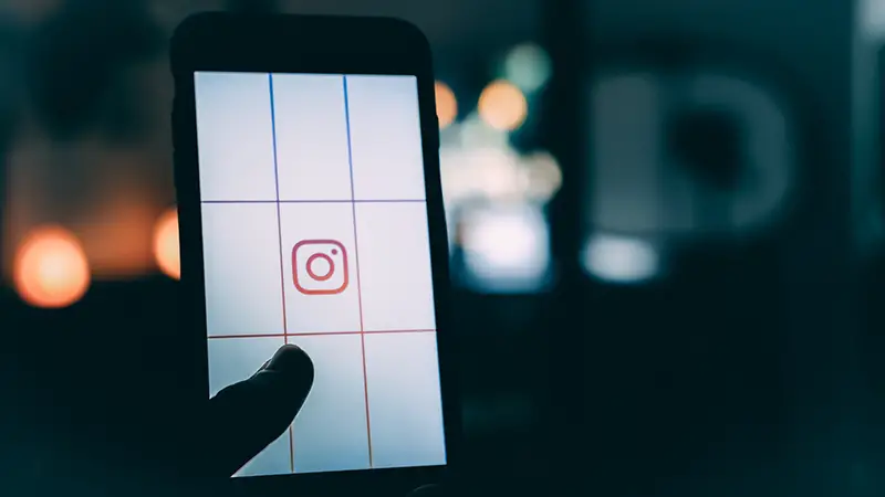 person using smartphone with Instagram logo screengrab and bokeh background