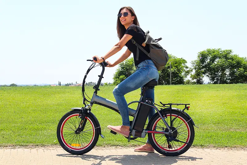 A smiling woman with electric bicycle in the park – e-bike