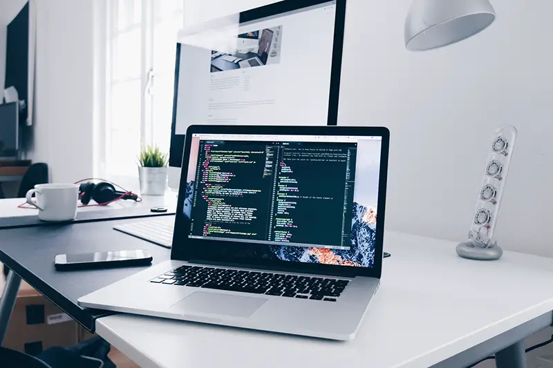 A macbook with lines of code on it's screen