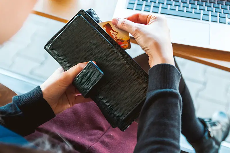 Person holding black long wallet with credit card