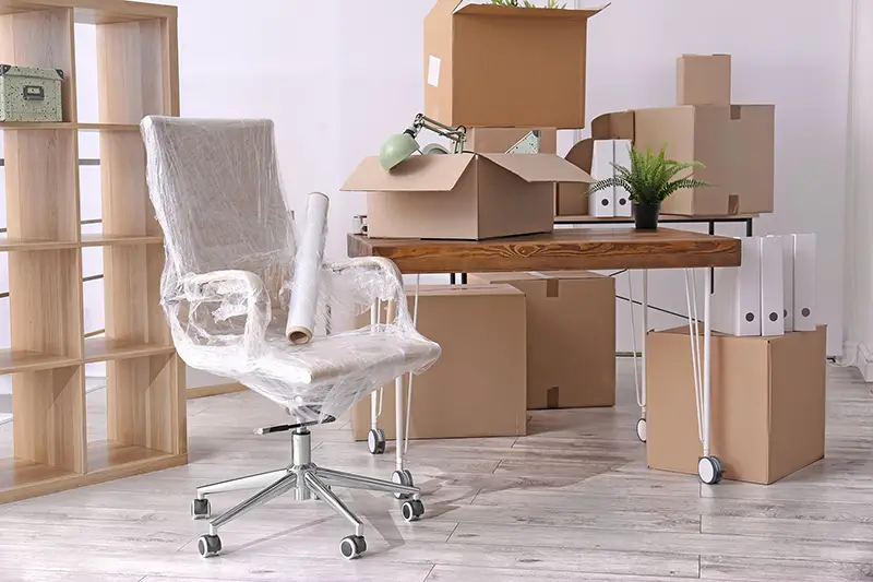 Office furniture and cardboard boxes with stuff in room. Office move concept.