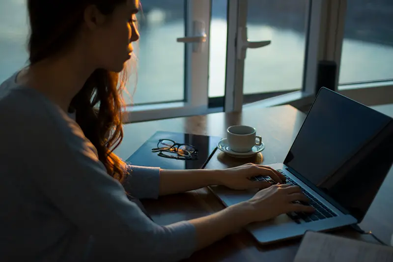 Woman sitting beside the table while working on her laptop