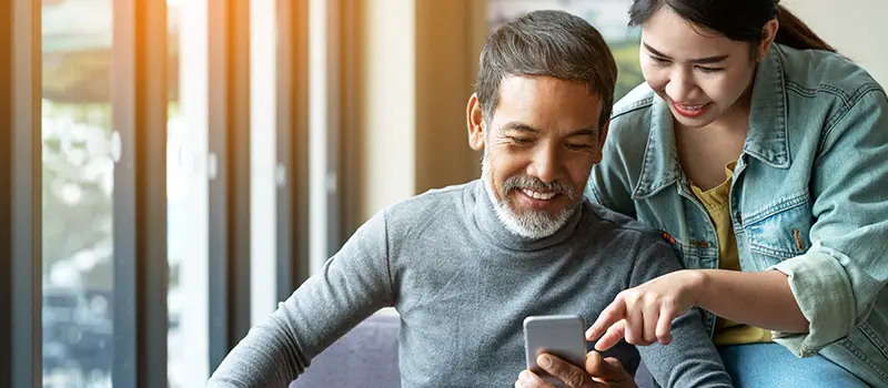 Man with beared and young woman using smartphone