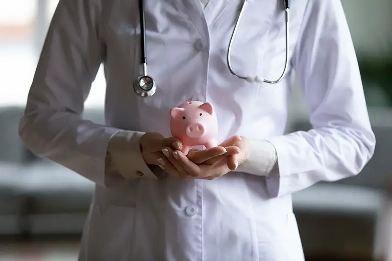 female doctor therapist wearing white coat uniform and stethoscope holding pink piggy bank,