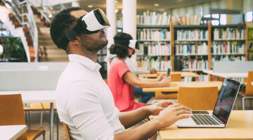 Male student training with VR simulator in library.