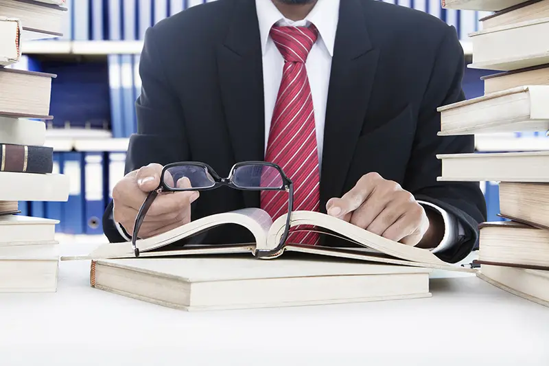 Businessman holding glasses and while reading business books