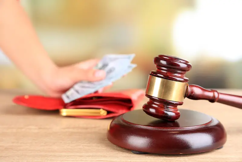 Gavel and hand holding money in wallet on wooden background