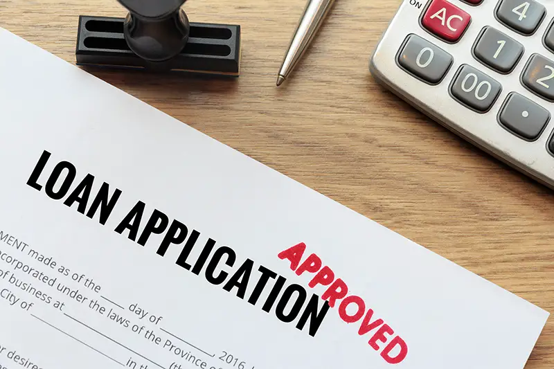 Approved loan application with rubber stamp and calculator concept