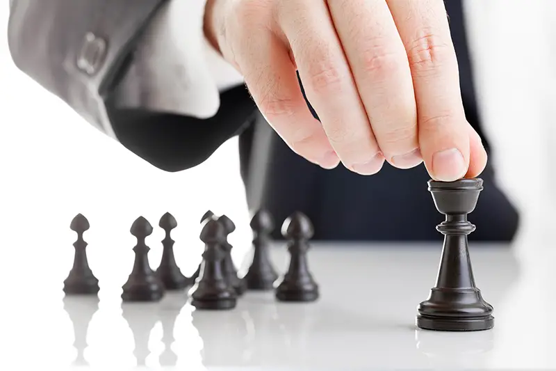 Business man moving chess figure with team behind - strategy, management or leadership concept